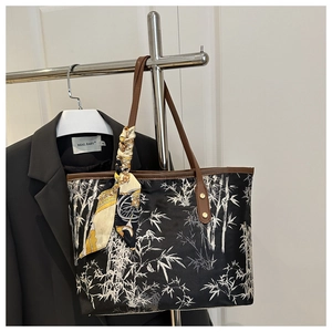 Detail of black tote bag with white bamboo print, leather handles and silk scarf