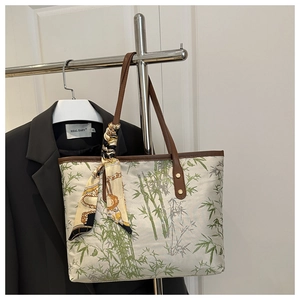 Detail of bamboo print tote bag with brown leather trim and printed silk scarf accessory