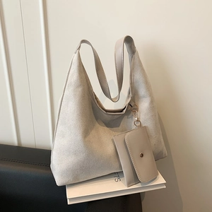 Minimalist beige suede large hobo tote bag with matching pouch on a white book
