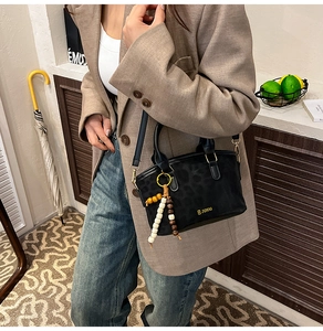 Dettaglio borsa vintage leopardata opaca con logo dorato e ciondolo in perline
