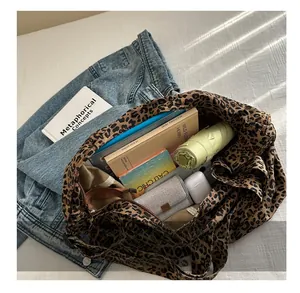 Spacious interior of leopard print canvas tote bag showing books, umbrella and headphones