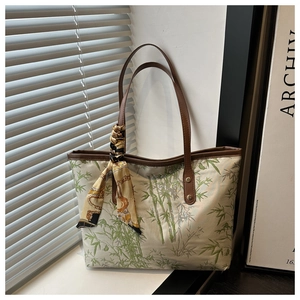 Close-up of cream tote bag featuring green bamboo print and elegant scarf detail