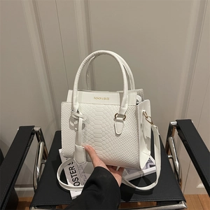 Sac à main blanc en cuir embossé avec logo doré posé sur un fauteuil moderne