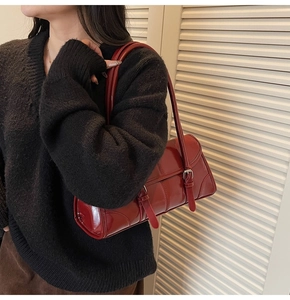 Close-up of vibrant red patent leather underarm bag with decorative silver buckle straps