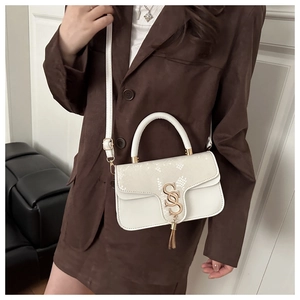 White snake pattern handbag with tassel detail and metal buckle worn by model