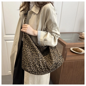 Detail shot of a large leopard print canvas tote bag on a model in a casual setting