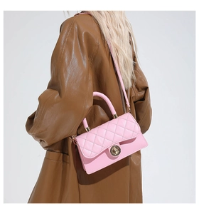Detalle de bolso acolchado rosa con cierre dorado y asa de mano combinado con abrigo de piel