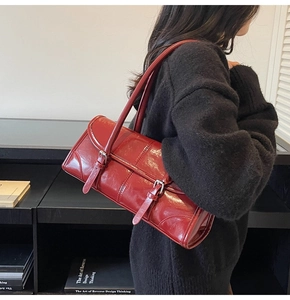 Detail of red glossy leather shoulder bag with vintage buckles and dual strap design