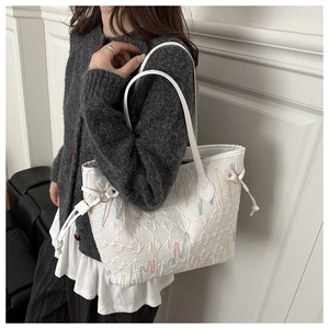 Detail of white tote bag with embossed letters and colorful embroidery on soft leather