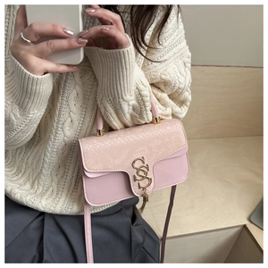 Detail of pink snake-embossed leather handbag with gold S-buckle and elegant fringe