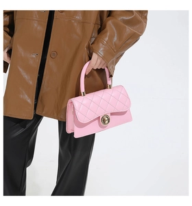 Detalle de bolso acolchado rosa con cierre cilíndrico dorado y asa a juego