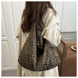 Rear view of a model wearing a large leopard print canvas tote bag over a beige coat