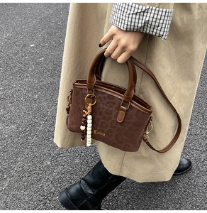 Détail du sac à main léopard avec pompon en perles de bois et logo de la marque