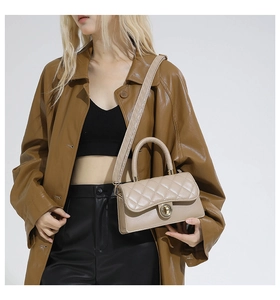 Bolso bandolera acolchado beige con cierre dorado lucido por una modelo
