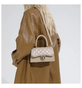 Primer plano del bolso acolchado beige con cierre dorado llevado por una modelo