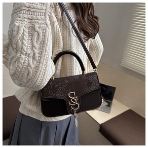 Detail of retro dark brown crossbody bag with snake skin texture and gold tassel clasp
