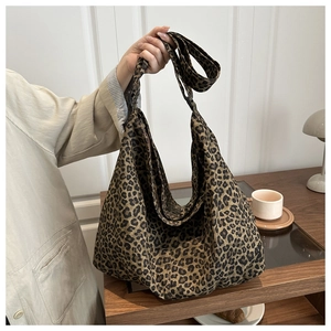 Close-up of leopard print canvas tote bag with wide shoulder strap in a cozy interior