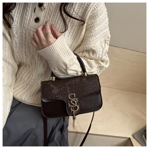 Close-up of snakeskin pattern flap and SS logo lock with metal tassels on dark brown bag