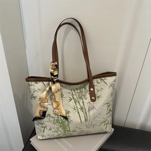 Canvas tote bag with green bamboo prints and brown leather handles with silk scarf