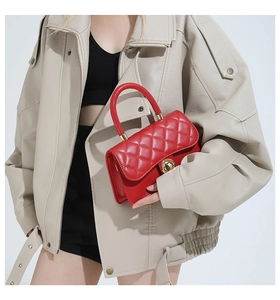 Modelo de moda con un pequeño bolso cuadrado acolchado rojo vibrante y herrajes dorados