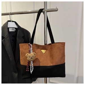 Macro view of two-tone tote bag with brown suede finish and golden triangle logo detail