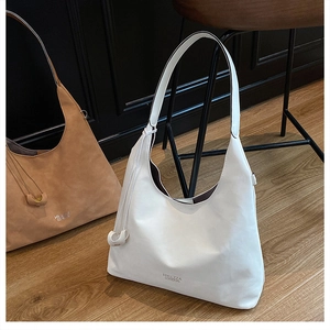 Detail view of large leather hobo bags in cream and brown on a wooden floor