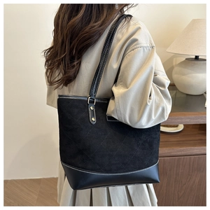 Quilted black tote bag with suede texture shown on shoulder for daily commute