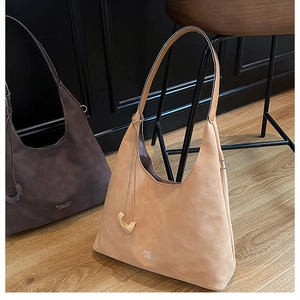 Detail of large brown hobo bags in matte leather with metal rings and half-moon charms