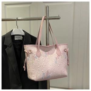 Detail of pink tote bag with diamond lattice embossing and colorful wave embroidery