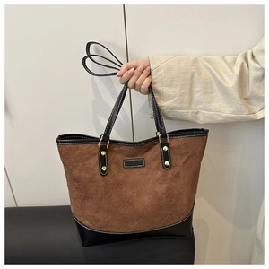 Detail of a large quilted brown suede tote bag featuring a black fashion logo tag