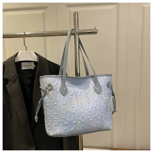 Detail of light blue tote bag featuring colorful wavy embroidery and side drawstring