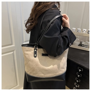 Detail of large tote bag with diamond quilted stitching and black leather strap worn by a model