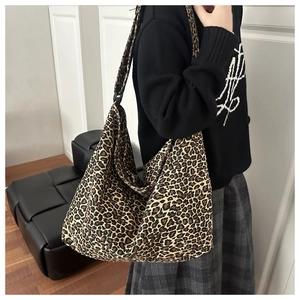 Side view of large leopard print hobo bag with wide shoulder strap on a model