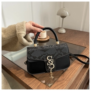 Close-up of black snake pattern leather handbag with gold S-buckle and metal tassel