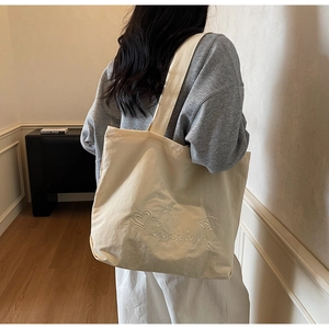 Détail de la broderie cœur sur un sac cabas en toile crème avec bandoulière large
