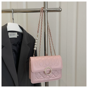 Detail of pink quilted bag with pearl buckle and metal chain strap decoration