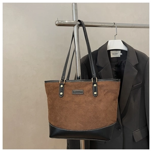Detailed close-up of brown suede tote bag with contrast stitching and Fashion label