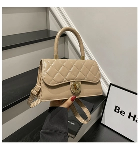 Detalle de bolso beige acolchado con cierre giratorio dorado y correa ajustable