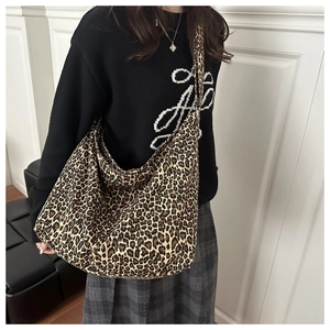 Close-up of leopard print canvas tote bag featuring large capacity and wide strap on model