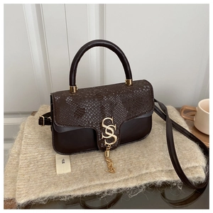 Detail of dark brown crossbody bag with snake skin texture flap and gold metal hardware