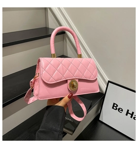 Detalle de un bolso de mano rosa acolchado con un elegante cierre de giro dorado