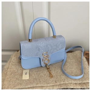 Detail of light blue crossbody bag with snake skin texture, gold logo and fringe tassel