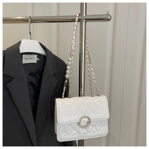 Detail of white quilted crossbody bag with pearl embellishments and metal chain strap