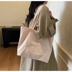 Détail du sac cabas rose avec broderie blanche de cœurs et d'étoiles en toile