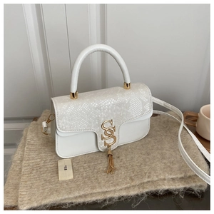 Detail of white faux leather crossbody bag with snake print flap and gold S-buckle tassel