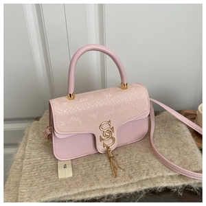 Pink crossbody bag detail featuring snakeskin texture flap and golden letter lock with tassel