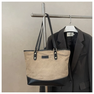 Detail of khaki quilted tote bag with black leather straps and fashion label tag