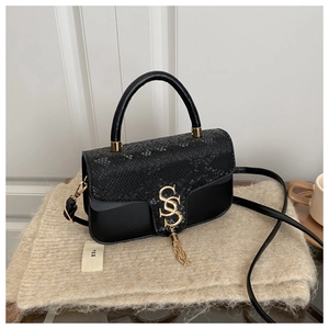 Detail of black crossbody bag with snakeskin flap and golden tassel lock on knit fabric