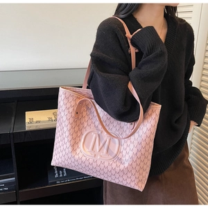 Detail of pink quilted tote bag featuring letter print and embossed logo on shoulder
