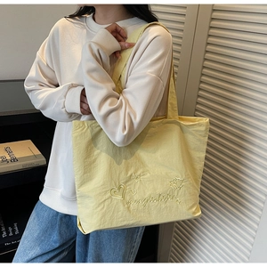 Détail du cabas jaune clair avec broderie de cœur et d'étoile sur tissu en nylon texturé